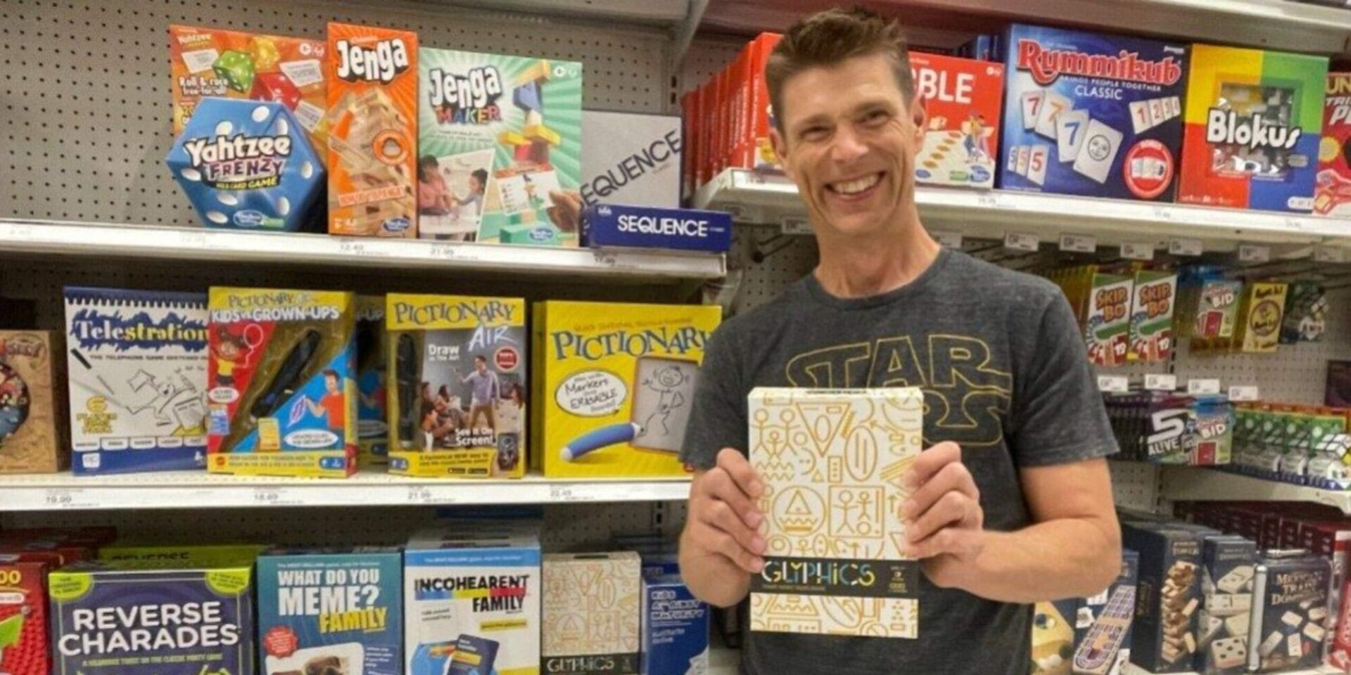 man smiling at the camera while holding a notebook